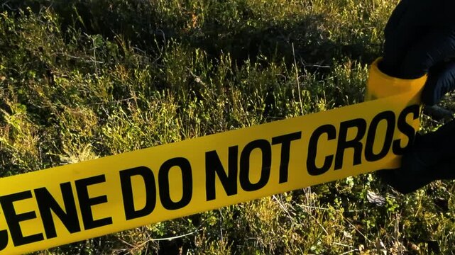 Investigator Unrolling Yellow Crime Scene Do Not Cross Tape