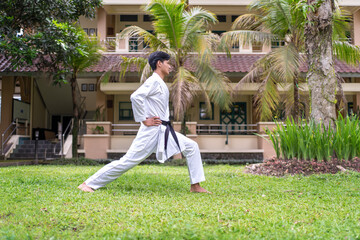 Fototapeta premium Asian Indonesian man practicing karate forward stance outdoors in martial arts training