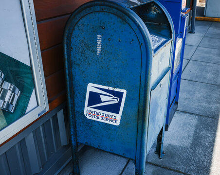 Ketchikan, Alaska, USA - July 26, 2025: A weathered blue United States Postal Service (USPS) collection mailbox on a sidewalk in downtown Ketchikan