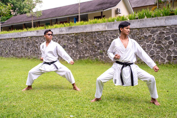 Fototapeta premium Asian Indonesian karate athletes practicing synchronized kata outdoors on grass