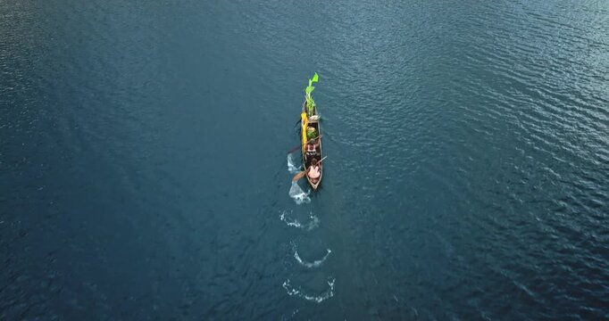 Solomon Islands - 01.13.2023: Two people woman paddling a traditional dugout canoe across the calm blue waters, remote tropical local life, transportation, logistic. Aerial view drone shot, top down