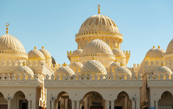Golden domes rise into the clear blue sky above the Al Mina Mosque in Hurghada, Egypt, with an intricate pattern placed in a sunny spot.