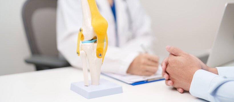 Doctor with Human Knee joint anatomy model. Osteoarthritis, Patellofemoral Pain Syndrome, Patellar Tendinitis, ACL, Anterior Cruciate Ligament, PCL, Posterior, MCL, Medial Collateral, LCL and Lateral