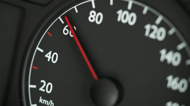 Close-up of a car speedometer showing 0 kmh with a red needle and blurred blue police lights in the background. Concept image for stopped vehicle, police control, traffic stop, road safety, law enfor