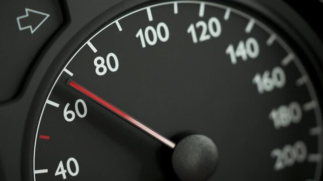 Close-up of a car speedometer showing approximately 60 kmh with a red needle and blurred blue police lights in the background. Concept image for speed control, traffic enforcement, road safety, polic