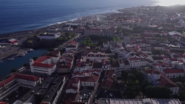 Aerial 4K drone footage of Ponta Delgada historic city, S&atilde;o Miguel, Azores, with commercial airplane on landing approach over Atlantic Ocean and traditional Portuguese architecture, Portugal.