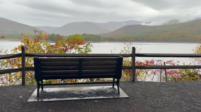 Bench overlooking Ashokan Reservoir on a rainy autumn day, with calm water, misty Catskill Mountains, and a quiet atmospheric landscape in New York.