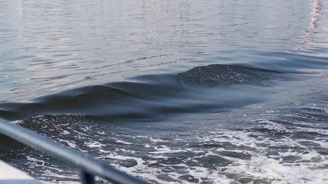 A steady side-angle shot from a moving vessel showing white foam and gentle waves created by the boat wake on calm water. Ideal for travel, vacation, and nautical themes with copy space.
