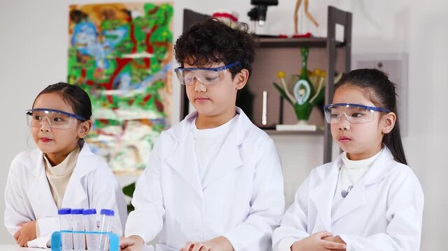 Asian Elementary Students in Lab Coats Conducting Science Experiments in Classroom