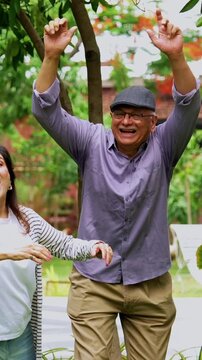 Senior friends enjoying throwing frisbee outdoors, Indian Asian elderly group playing with flying disc in garden, smiling and laughing together while celebrating reunion in lush green nature setting