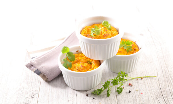 homemade vegetable flan in white ramekins with fresh herbs on wooden background