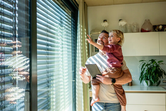 Father showing smart home control to toddler while managing exterior shading system.