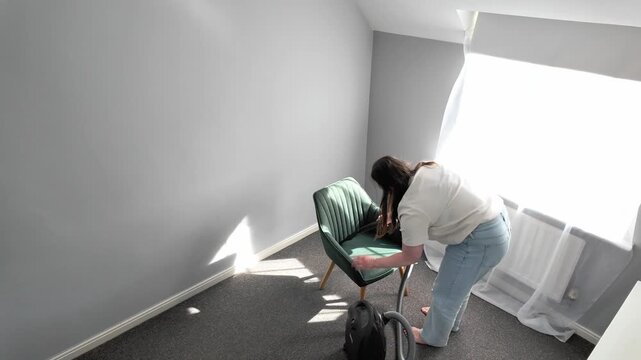 Overhead view of woman vacuum cleaning chair