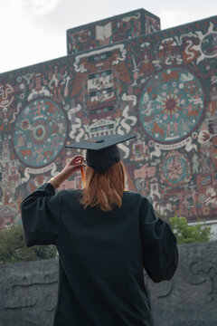 A young woman, seen from behind, wearing a graduation gown and cap