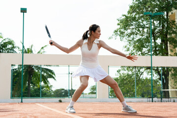 Fototapeta na wymiar Asian young sportswoman exercise, playing tennis on outdoor clay court. 