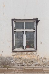 Fototapeta premium Traditional wooden casement window is set within a white stucco facade showing signs of age and deterioration, Saaremaa, Estonia, Europe.
