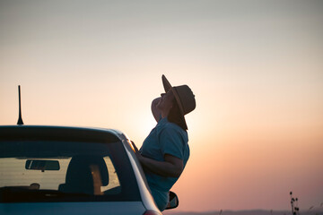 Naklejka premium Girl with hat in the window of the car. Adventure, vacation, road trip concept.