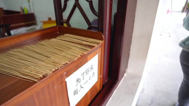 Close up of a hand picking up an incense stick from a wooden dispenser in a Chinese temple