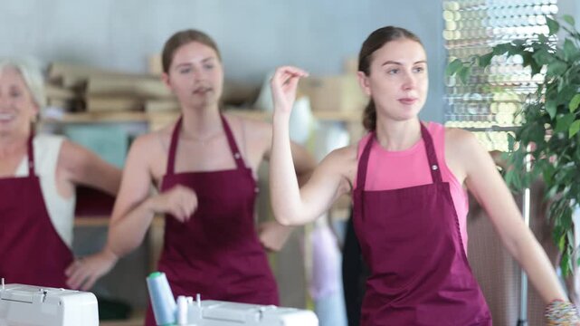 Team of dressmakers stands in the workshop and does a warm-up after a long work. Seamstresses stretch their muscles after sedentary work. High quality 4k footage