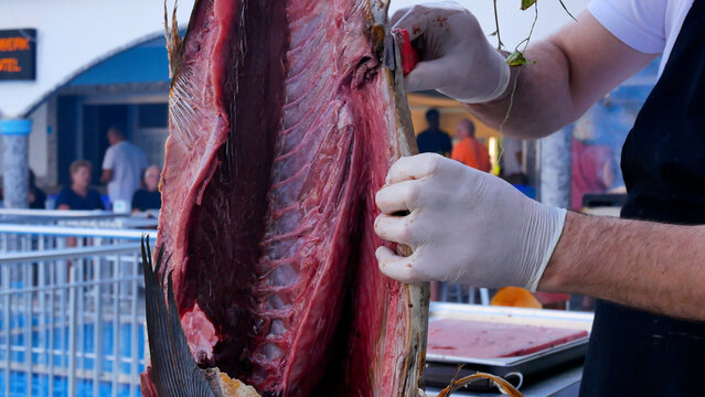 Chef cutting and gutting a large fish in a restaurant kitchen before cooking. Concept of seafood preparation, professional culinary process, and healthy seafood dishes. Fresh fish as part of a