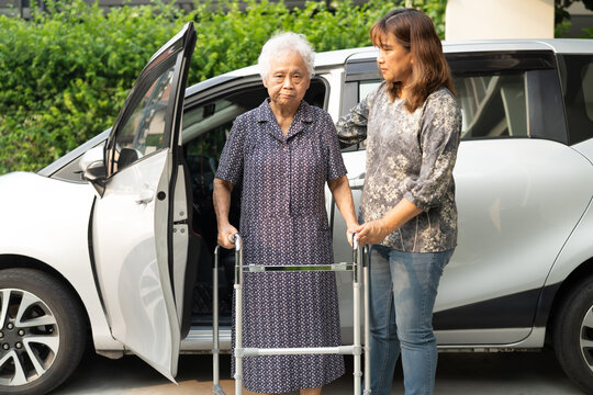 Caregiver help Asian elderly woman disability patient get in her car.
