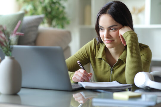 Satisfied student studying taking notes and watching online lesson