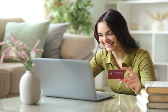 Happy young woman paying online using card and computer