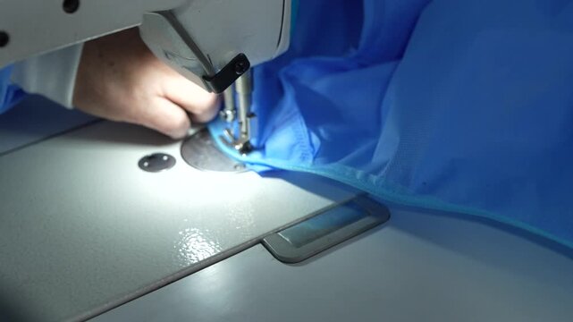 The process of making a disposable medical gown from recycled fabric on a sewing machine, sewing, medical clothing, blue fabric