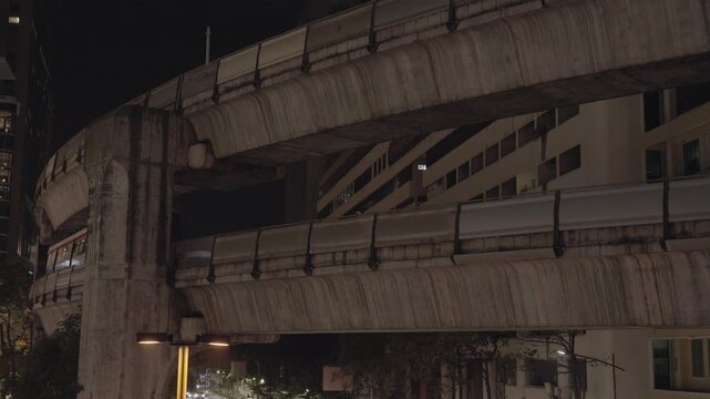 view look upto skytrain track way bridge in the city center of Bangkok metropolis in night time,Bangkok public transportation skytrain system
