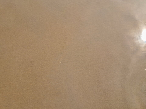 Clean tropical beach sand surface with water reflection