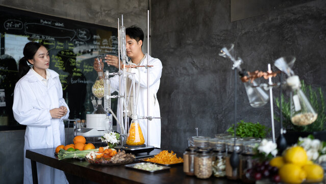 Male and female researchers conduct botanical distillation in a lab setting with fresh herbs and fruits, ideal for science, wellness, and aromatherapy concepts