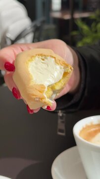 Traditional Italian Sospiri dessert, also known as Sise delle Monache or Tette delle Monache, served in Matera, Italy. Soft sponge pastry with creamy filling in a cozy Italian cafe. Vertical video.