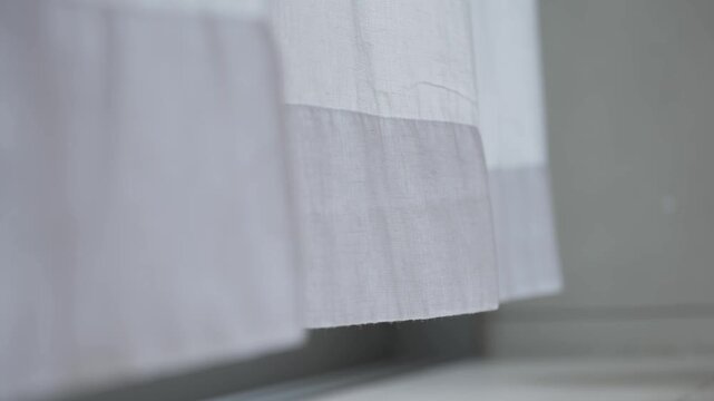 Wind blows the curtain or sways blind in the house or hotel bedroom living room. Sunny day with sun shines through the tulle through the window calm quiet morning curtain texture background.