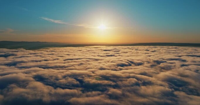 Flying above thick layer clouds sunset time. Golden sunlight shining over fluffy white textures. Peaceful atmospheric background travel tourism inspiration concept.