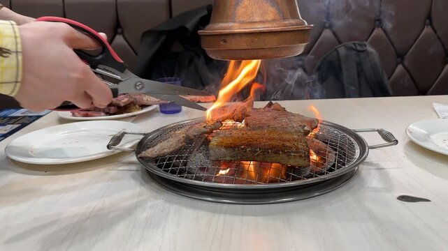 Grilling meat over an open flame in a restaurant kitchen during a late evening meal