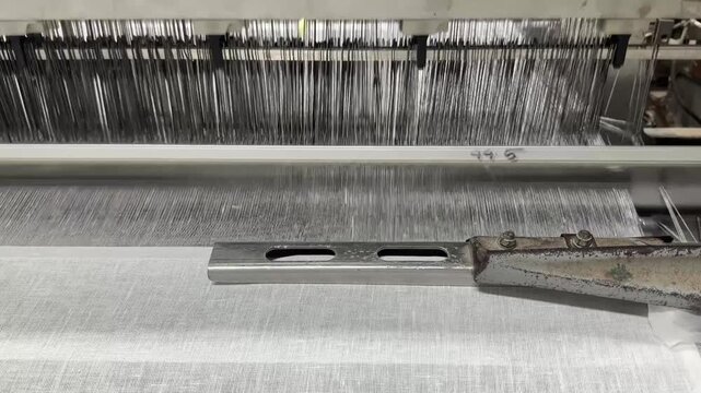 Close-Up of Automated Textile Weaving Machine Producing Fabric in Factory