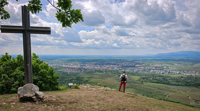 Landscape photo of a hiker overlooking Eger and the distant M&aacute;tra Mountains from Nagy-Eged Hill in northern Hungary.