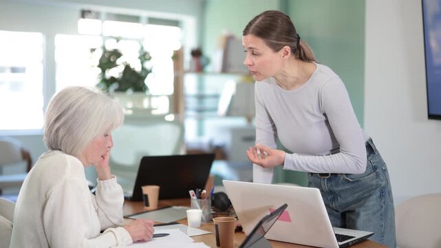 Upset senior female employee is reprimanded. Boss yells at subordinate at background. Person is upset because of critique from superiors. High quality 4k footage