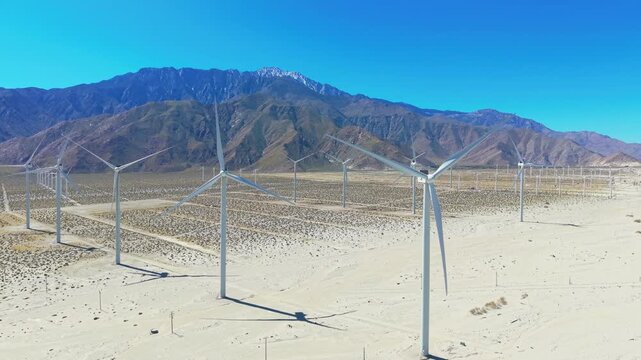 Wide aerial panorama of windmills across Palm Springs desert landscape with mountains and dry terrain scener.