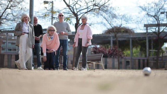 Focused elderly people concentrated on the competition while playing petanca in park