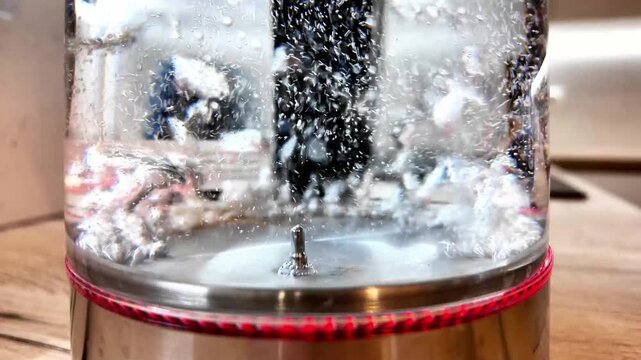 Violent Water Turbulence Inside Glass Kettle Creating Chaotic Splash And Large Bubbles, Energetic Kitchen Scene With Stainless Base And Bright Led Rim, High Motion Study Of Liquid Dynamics