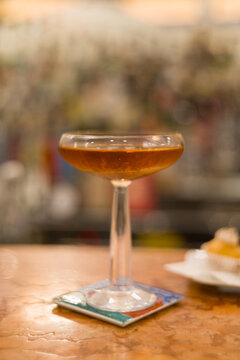 Elegant and sophisticated cocktail served on a professional bar counter. The image features a beautifully garnished drink in a stylish glass, set against a background of blurred liquor bottles
