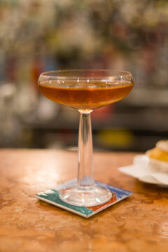 Elegant and sophisticated cocktail served on a professional bar counter. The image features a beautifully garnished drink in a stylish glass, set against a background of blurred liquor bottles