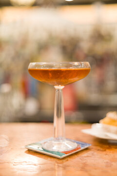 Elegant and sophisticated cocktail served on a professional bar counter. The image features a beautifully garnished drink in a stylish glass, set against a background of blurred liquor bottles
