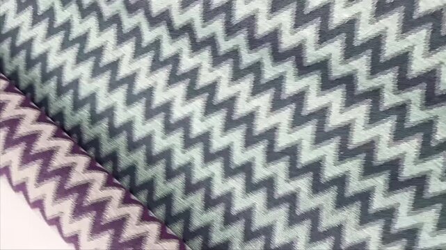 A durable upholstery fabric features a reversible design with purple and green chevron zig zag patterns in a textured jacquard weave for furniture and modern home decor projects