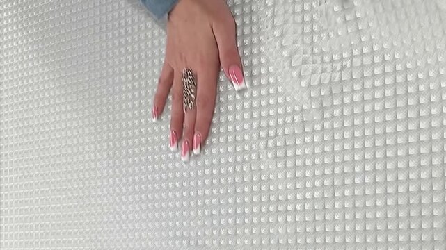 The elegant white quilted fabric showcases a sophisticated geometric diamond pattern with a subtle metallic sheen. This high quality material is perfect for modern interior design and upholstery.