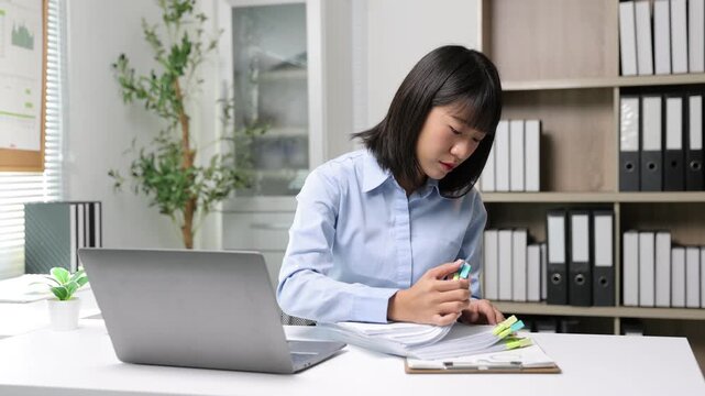Young Asian businesswoman organizing documents at her office desk.