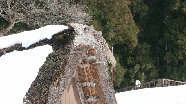 view to top of roof of gassho zukuri house in shirakawago village full with snow covered on the roof surface in winter daytime. snow on roof of heritage house in Japan