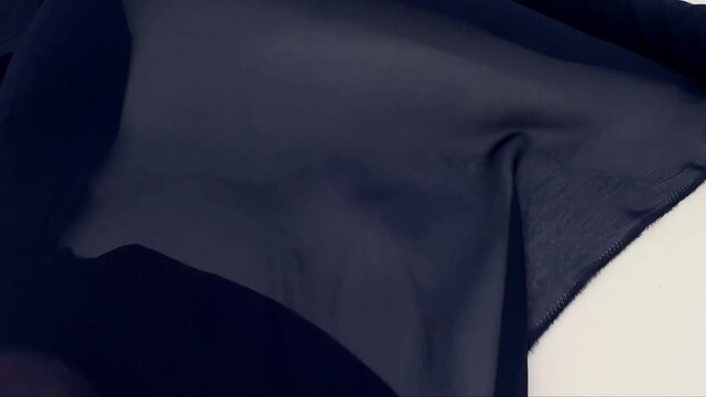 The lightweight navy blue chiffon fabric features a delicate sheer texture and elegant drape. This translucent textile is ideal for creating flowy evening wear bridal gowns and soft fashion layers.