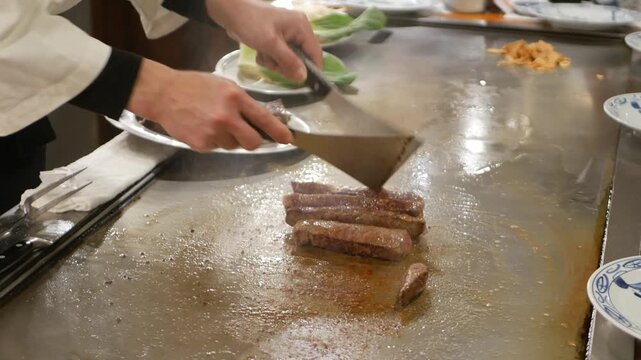 POV to kobe sirloin wagyu steak while cooking on teppan yaki flat pan in japanese style restaurant for lunch time. Chef cooking wagyu kobe beef sirloin steak on teppanyaki flat pan